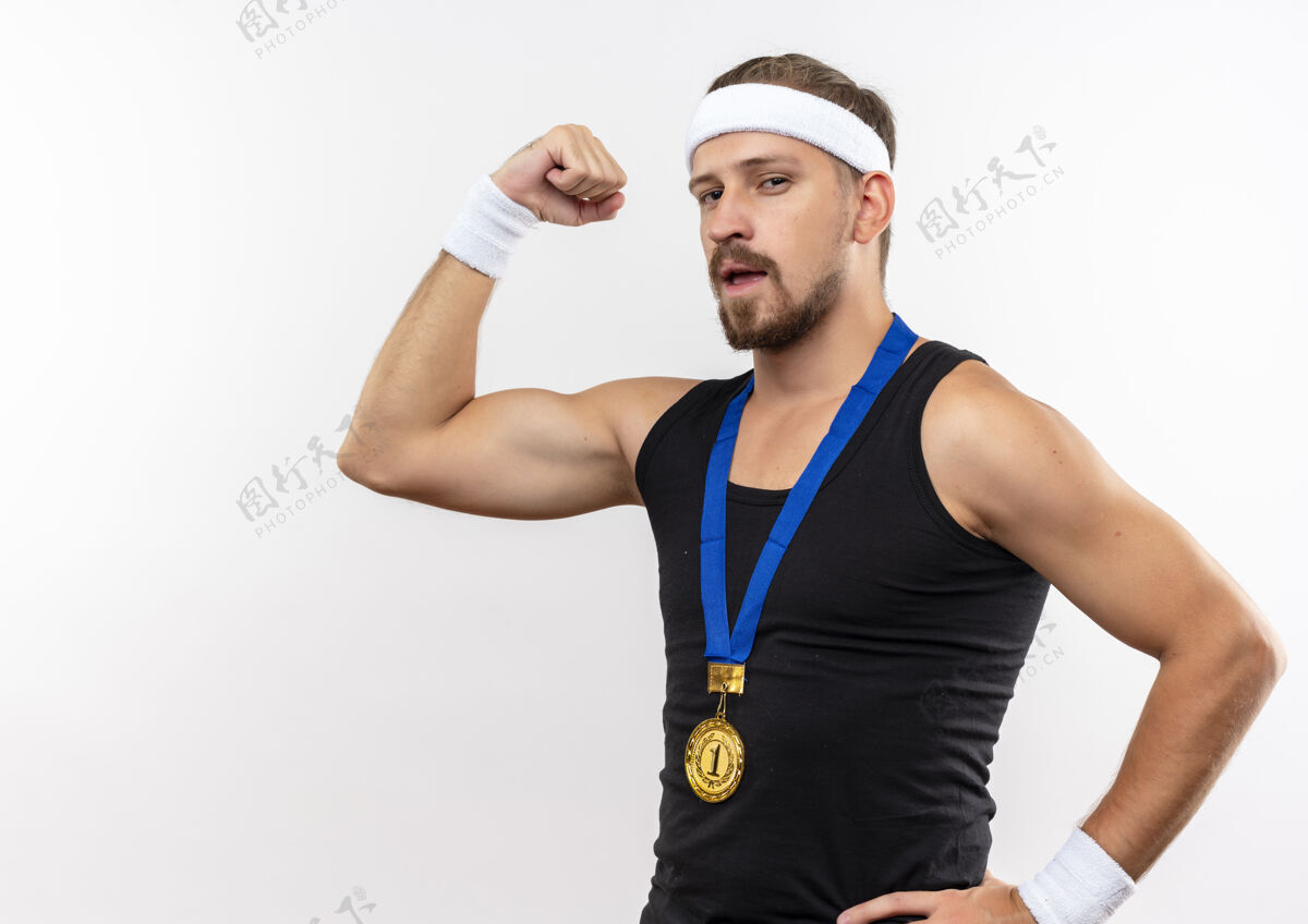 头带自信的年轻帅气的运动型男人戴着头带和腕带 手放在腰上 在白色的墙壁上孤立着 有复制空间强壮手势手