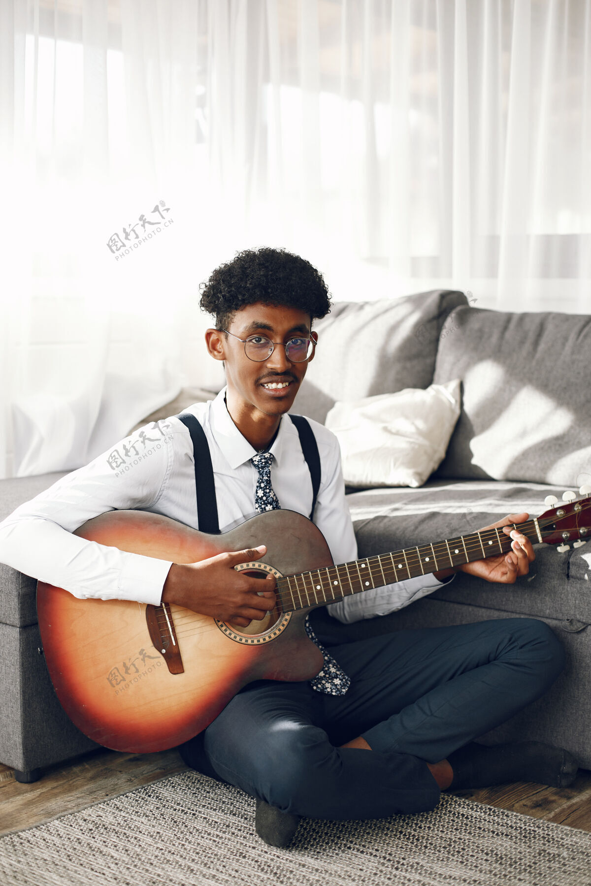 中间Hoobies概念穿着紧身衣的印度年轻人坐在客厅里音乐家在弹吉他课音乐家男性