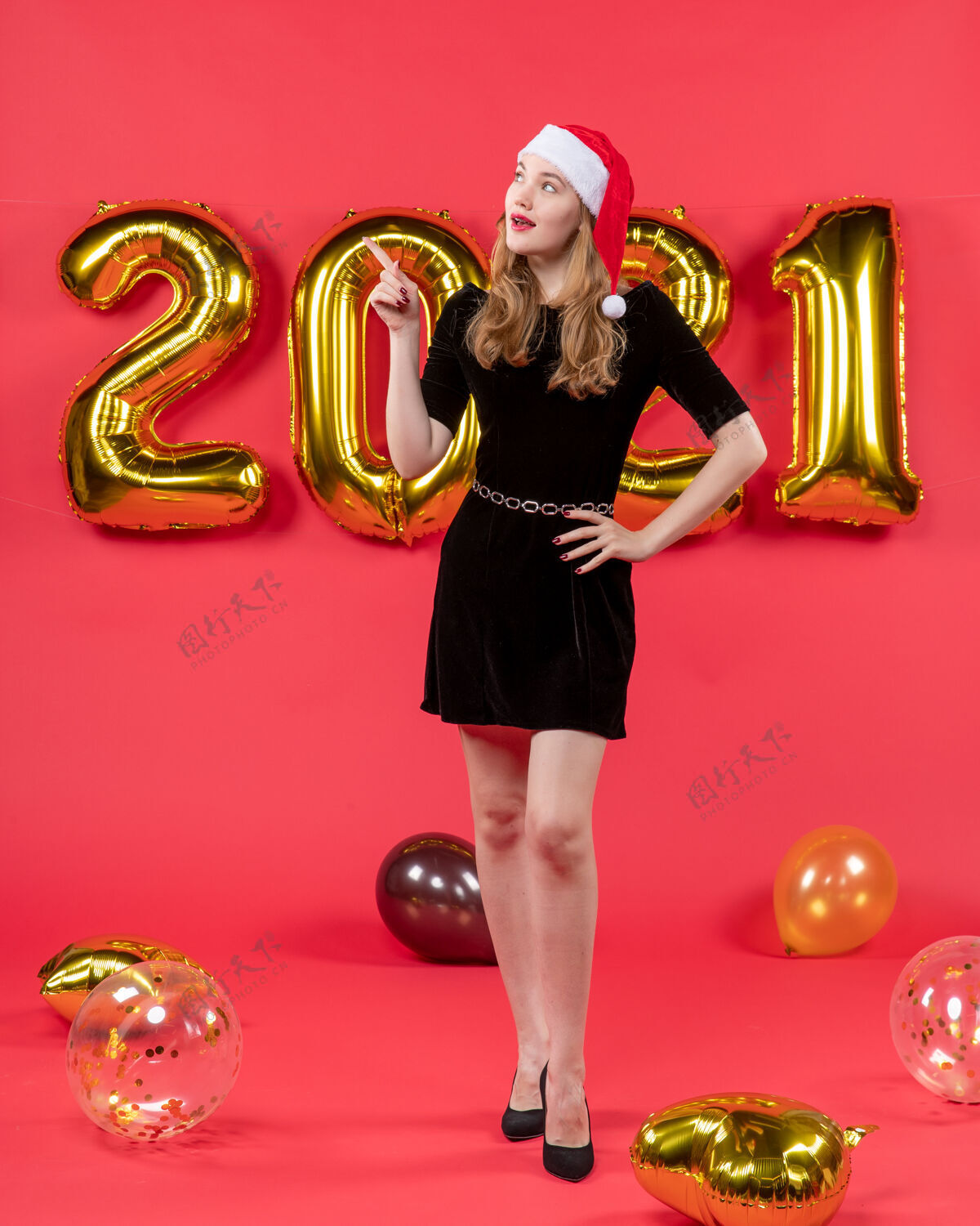 姿势正面图年轻漂亮的女人穿着黑色的衣服气球指着红色的东西身体漂亮黄铜