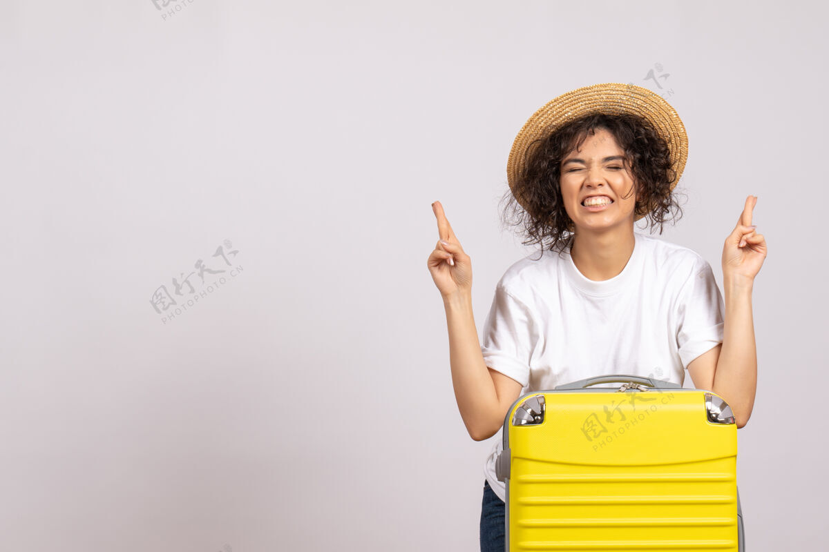休息正面图：年轻的女性 带着黄色的包 准备旅行 在白色的背景色上交叉手指度假飞行旅游飞机休息航行微笑包手指