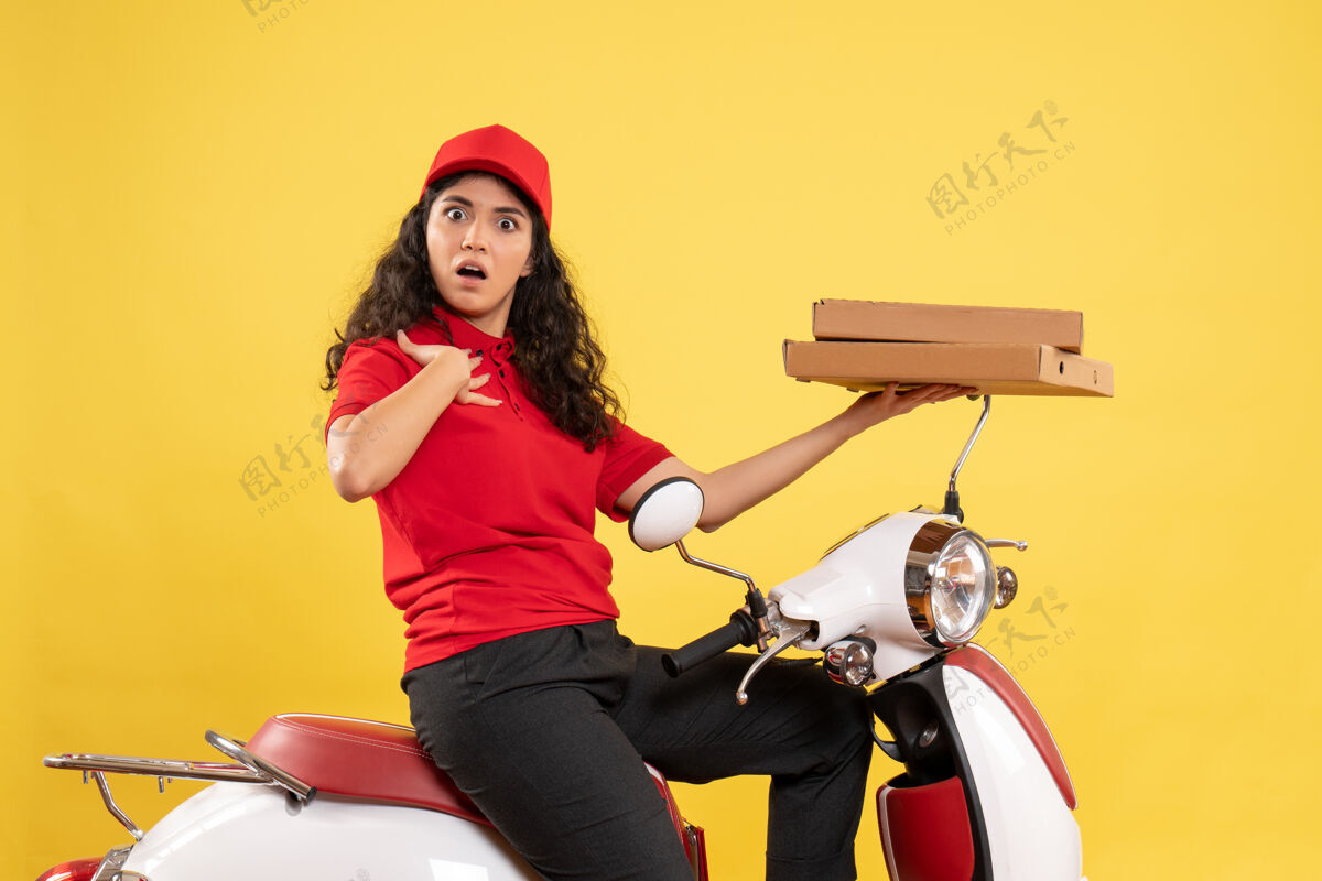 人正面图骑自行车的女快递员拿着披萨盒在黄色办公桌上服务制服工作的女快递员工作工人成人车辆