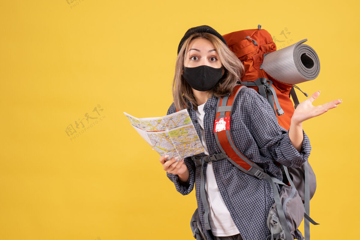 背包迷惑不解的旅行女孩带着黑色面具和背包拿着地图肖像保护面具