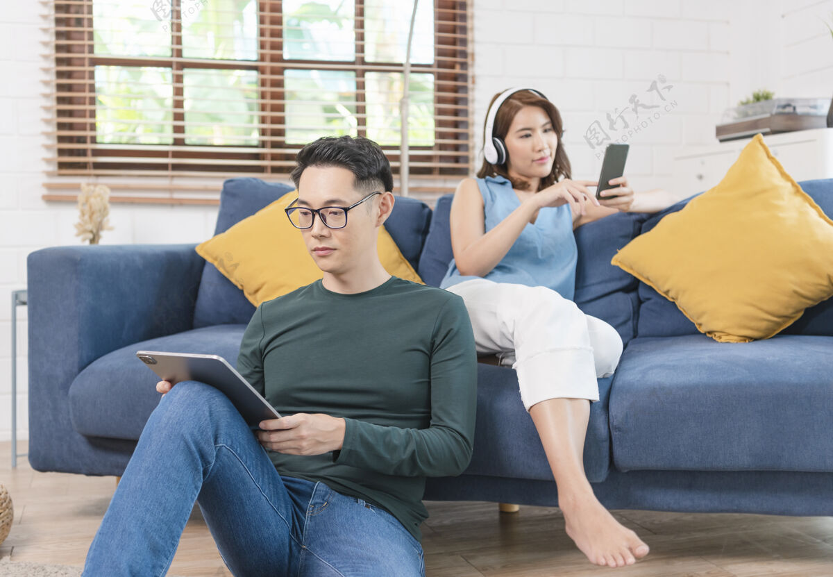 上瘾这对幸福的亚洲夫妇正在家里的沙发上共度周末 放松身心 享受上网的乐趣无线沙发周末