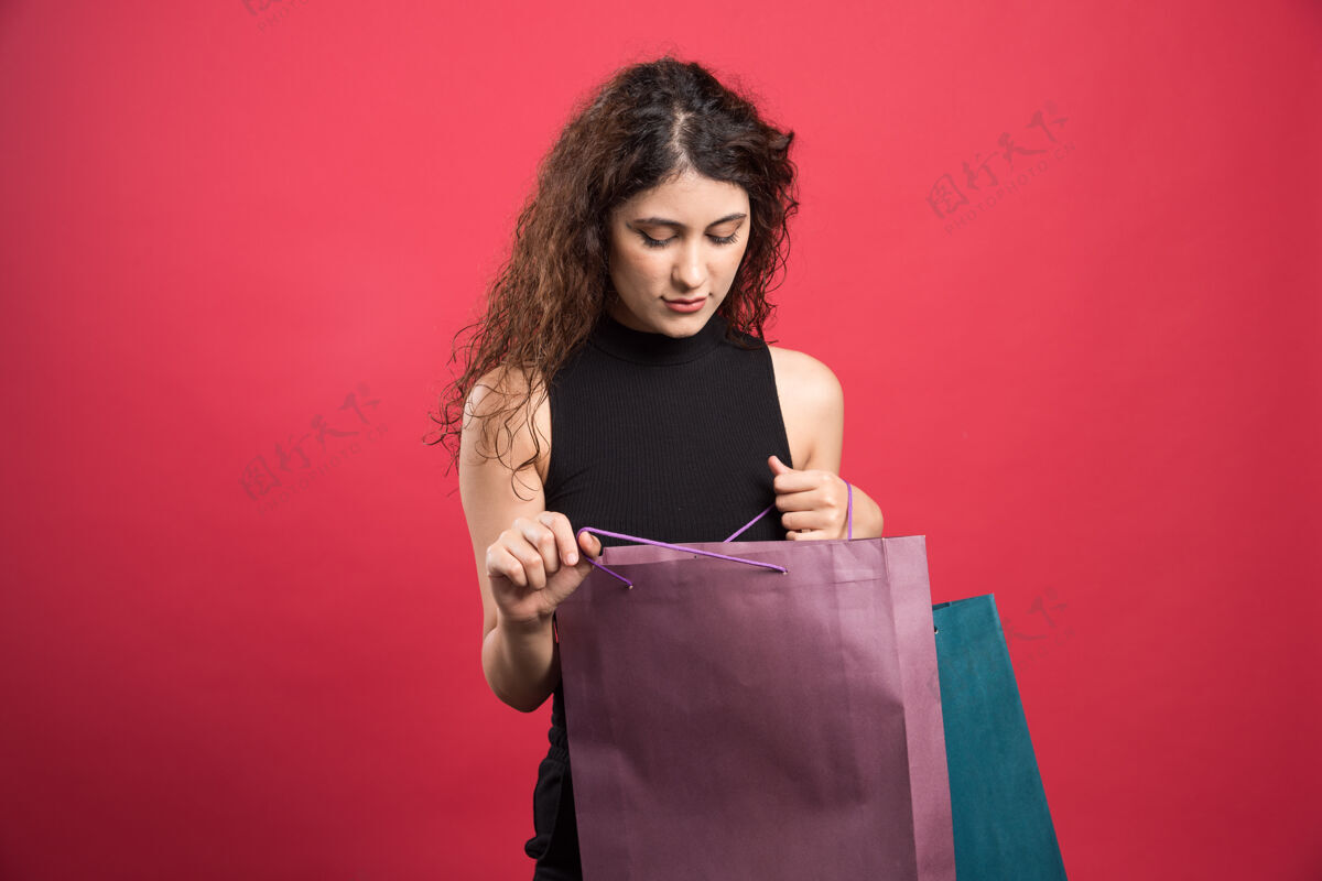 卷发女人在看一个红色的包时尚包女士