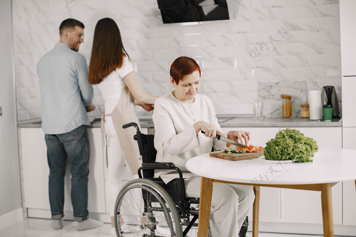 年龄轮椅上的老太太在厨房做饭残疾人夫妇在帮她独立桌子切割