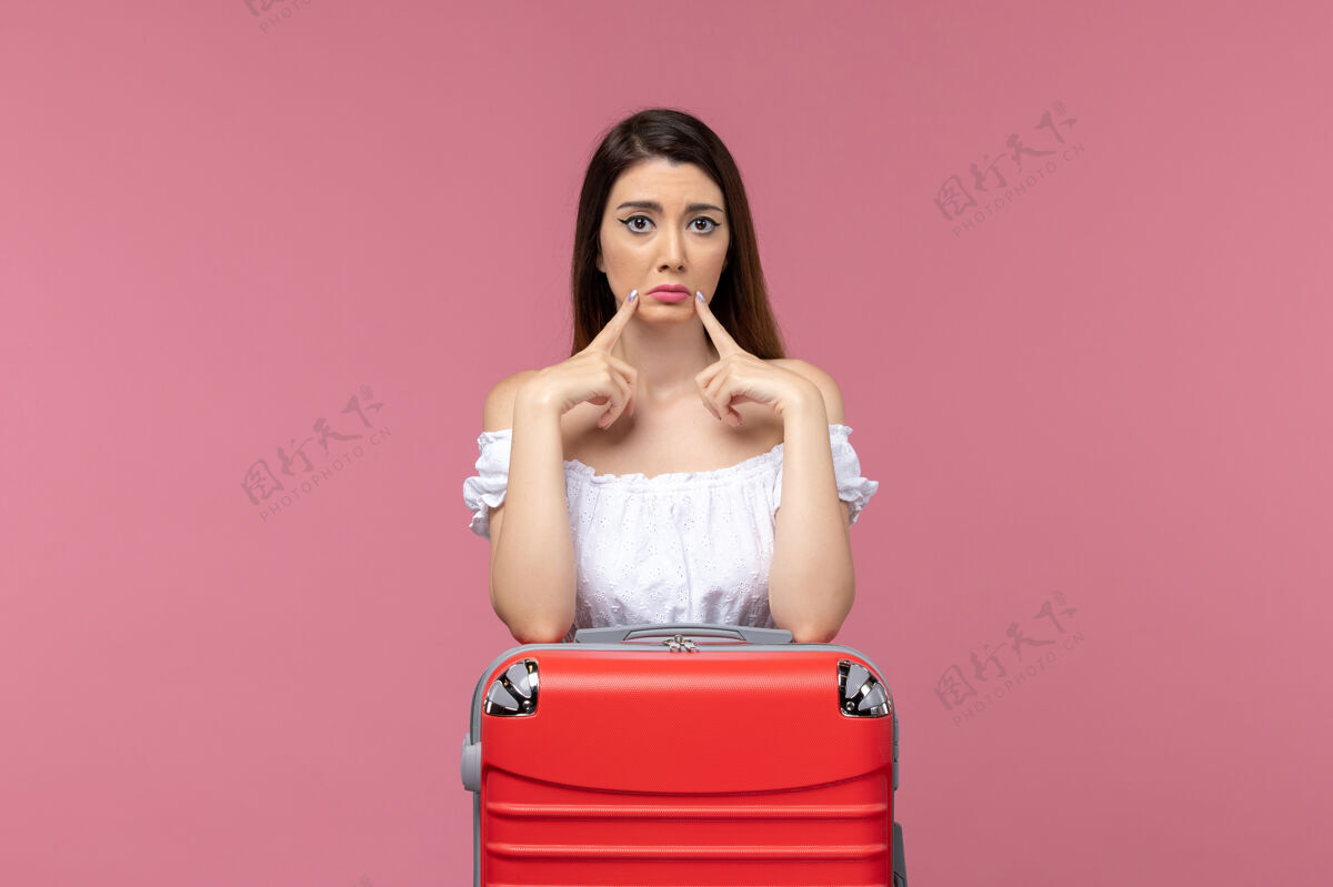 黑发正面图年轻女子站在一个粉红色的背景旅行海上旅行妇女出国度假准备度假旅行年轻女子成人