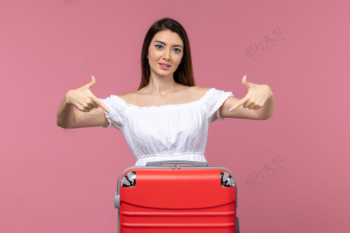 年轻女子正面图年轻女子站在粉红色的背景上准备度假海上旅行海外旅行人成人女士