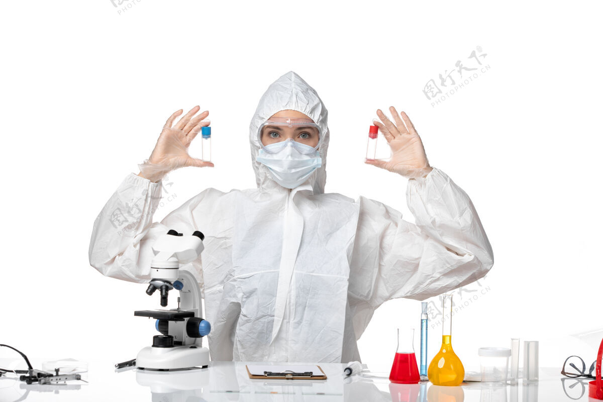 外套正面图年轻女医生穿着白色防护服带口罩因柯维德手持烧瓶背景白色大流行飞溅病毒健康柯维德-病毒医学实验室外套