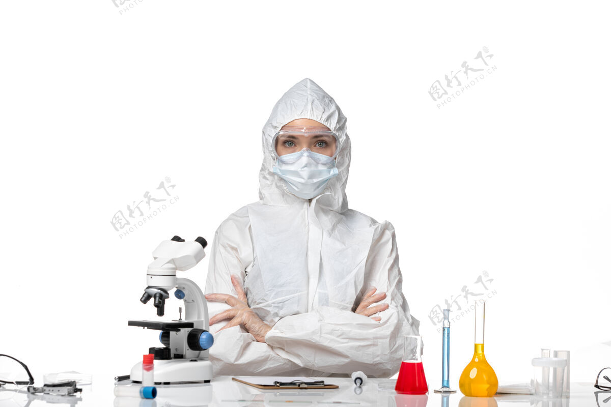 医疗正面图年轻女医生穿着防护服 戴着口罩 因为柯维德坐在浅白的背景上大流行着柯维德病毒专业套装防护