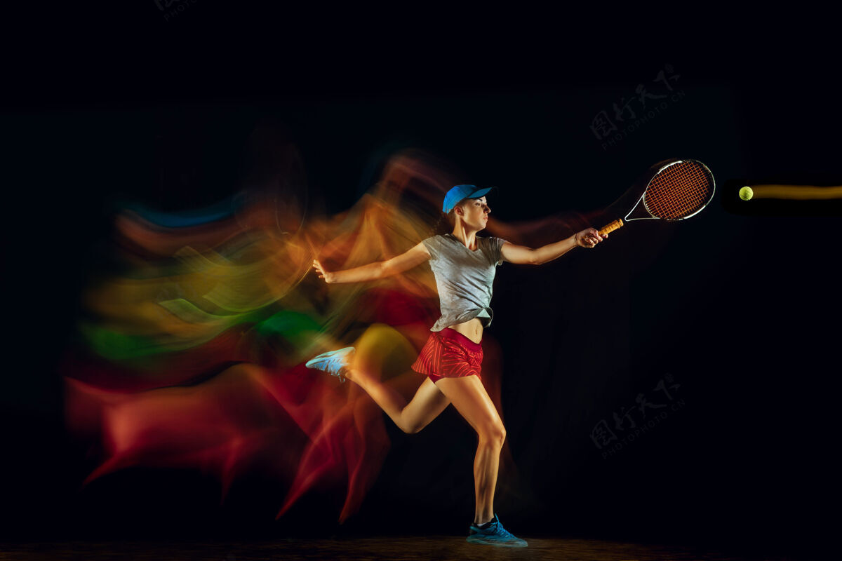 成人一个打网球的女人孤零零地站在黑色的墙壁上 混合着柔和的光线健身明亮运动