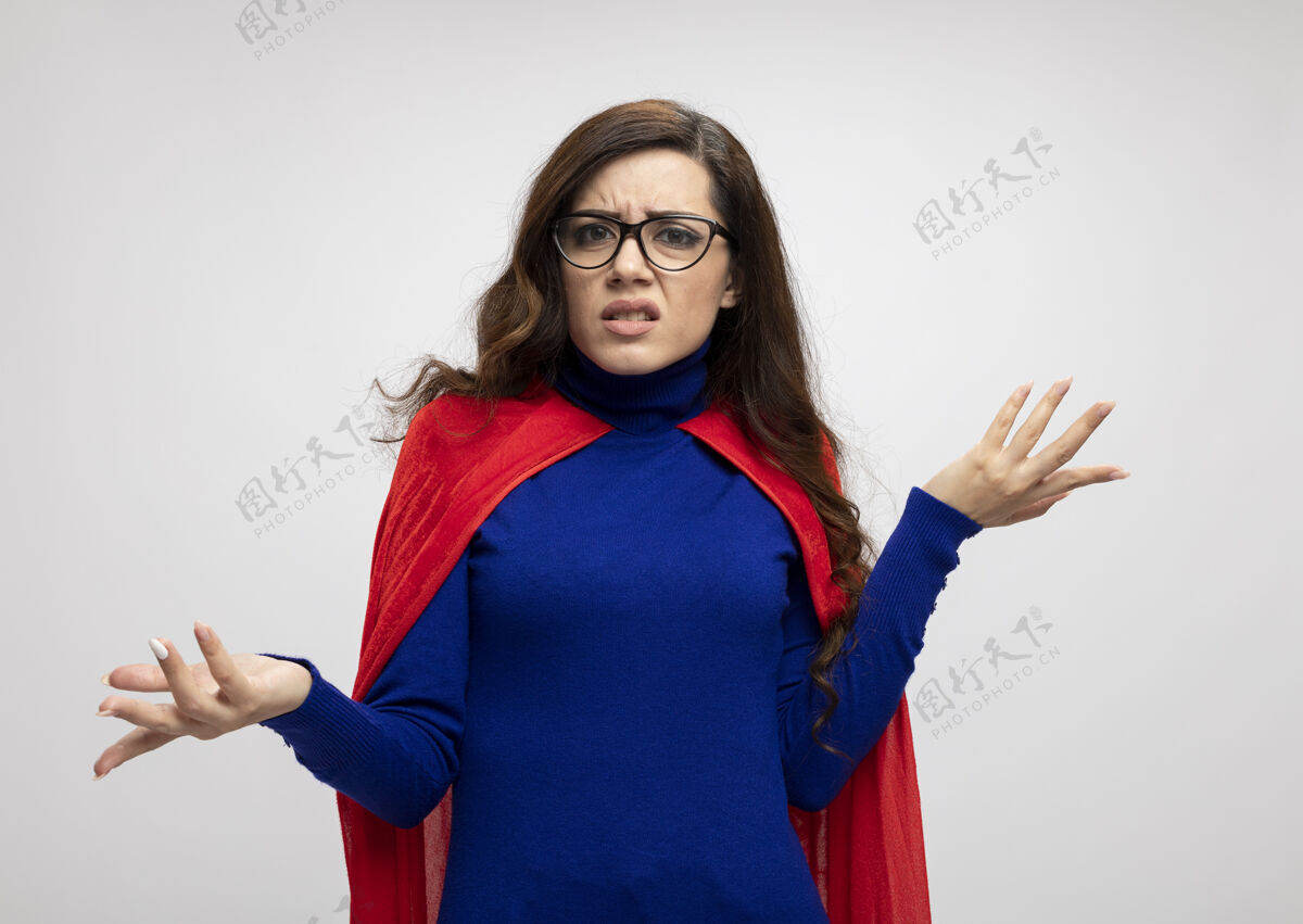 超级英雄无知的高加索超级英雄女孩戴着眼镜 披着红色斗篷 双手张开放在白色的脸上无知斗篷光学