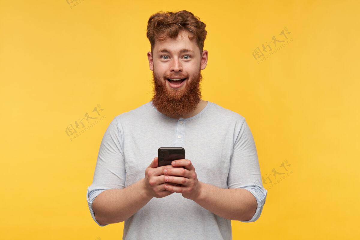 帅气一个大胡子的年轻人拿着他的手机 脸上带着震惊的表情学生脸发型