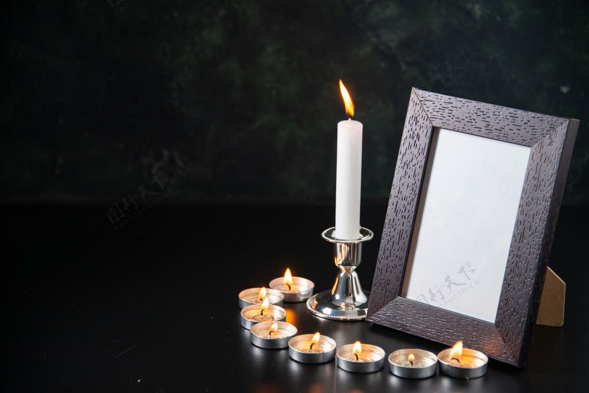 记忆燃烧的蜡烛作为黑色表面上坠落的记忆的正面视图蜡烛前面燃烧