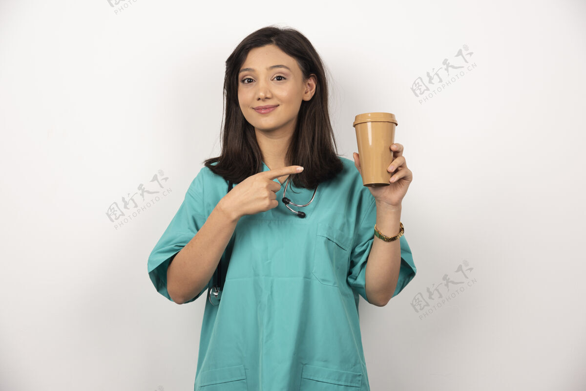 职业女医生指着白色背景上的咖啡杯高质量的照片杯子健康工作