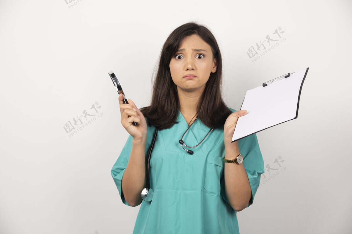 制服女医生拿着笔和剪贴板看着白色背景上的相机高质量的照片保健剪贴板女性