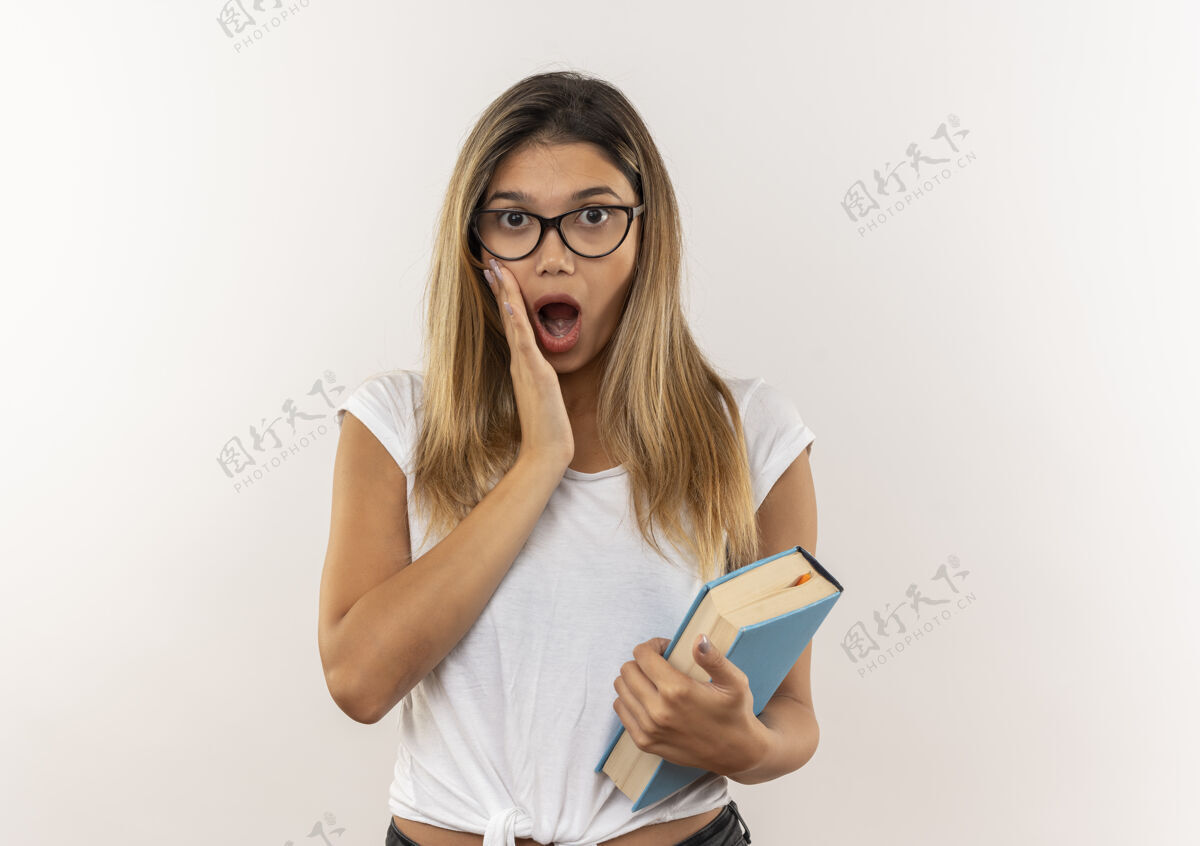 漂亮惊讶的年轻漂亮的女学生戴着眼镜 背着书包 手放在脸颊上 隔离在白墙上手人背