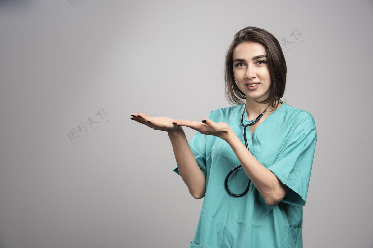 听诊器身着制服的年轻医生在灰色背景上做手势高质量照片医疗医生工作