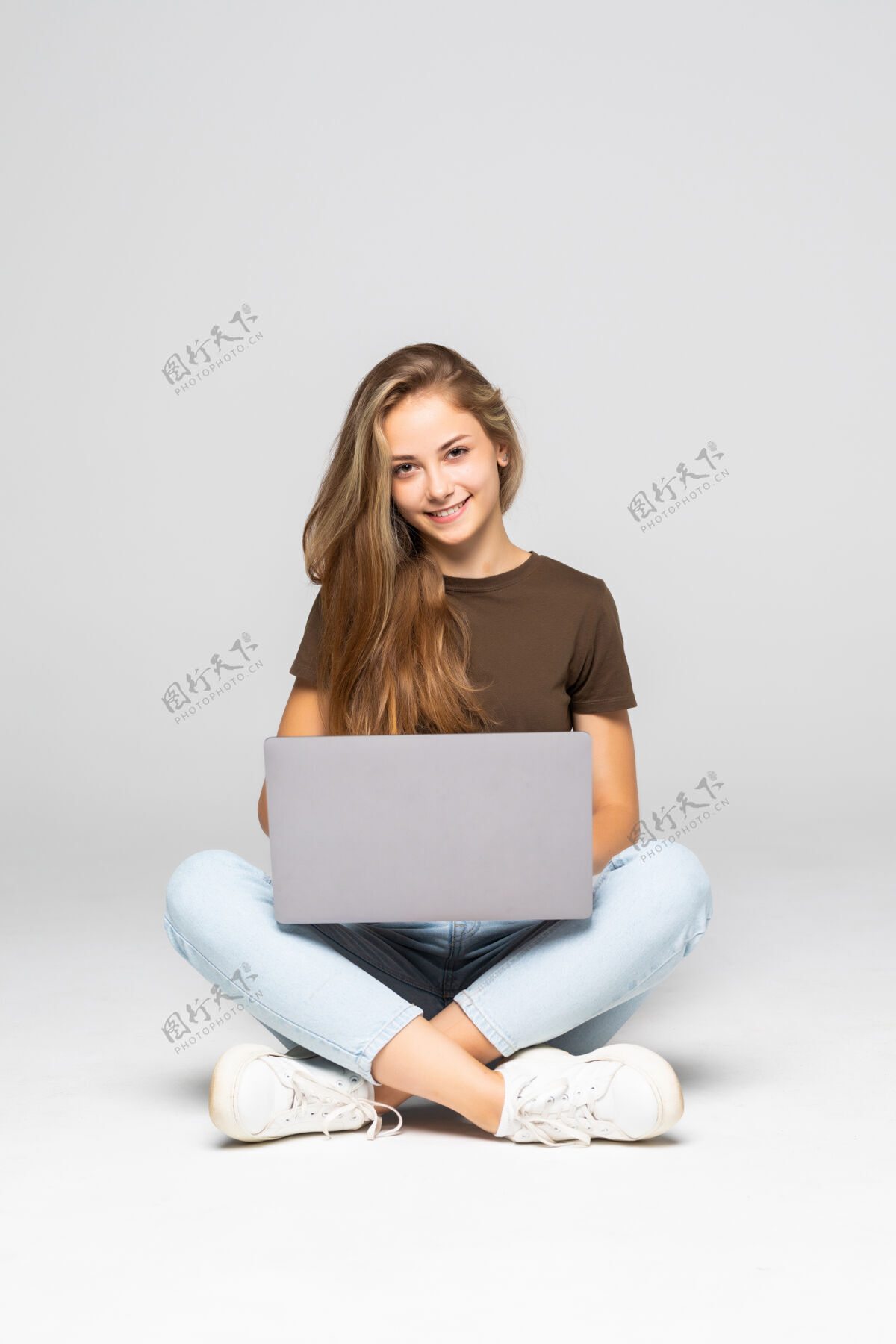 电脑年轻随意的女人坐下来微笑着拿着笔记本电脑隔离在白墙上笔记本电脑成人空间