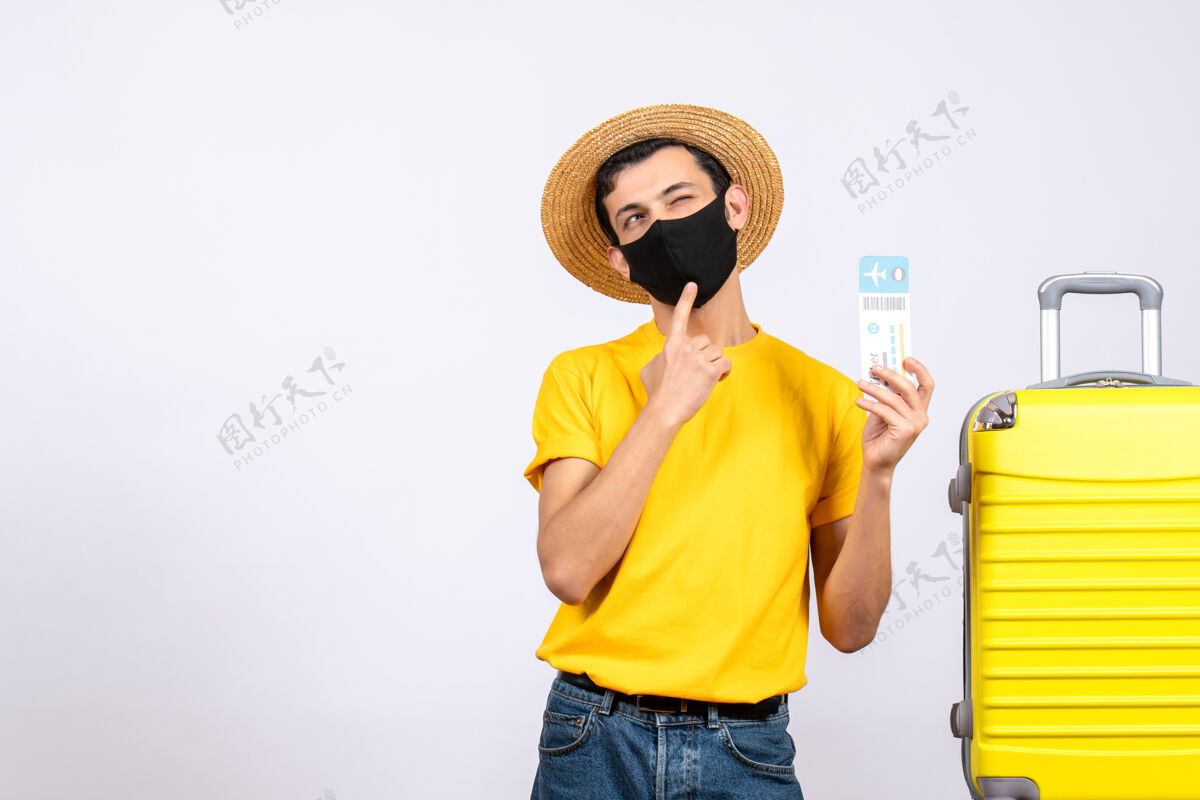 T恤正面图穿着黄色t恤的年轻人站在黄色手提箱旁举着旅行票眨眼年轻人前面黄色
