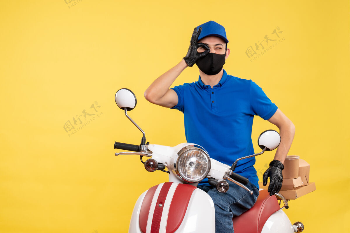 病毒正面图黄色背景上穿着蓝色制服的年轻男性快递员乔维德-工作大流行病毒送货自行车工作视图工作制服