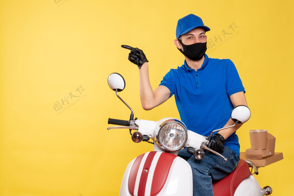男性正面图：身穿蓝色制服 戴着黄色背景面具的年轻男性信使送货前面蓝色