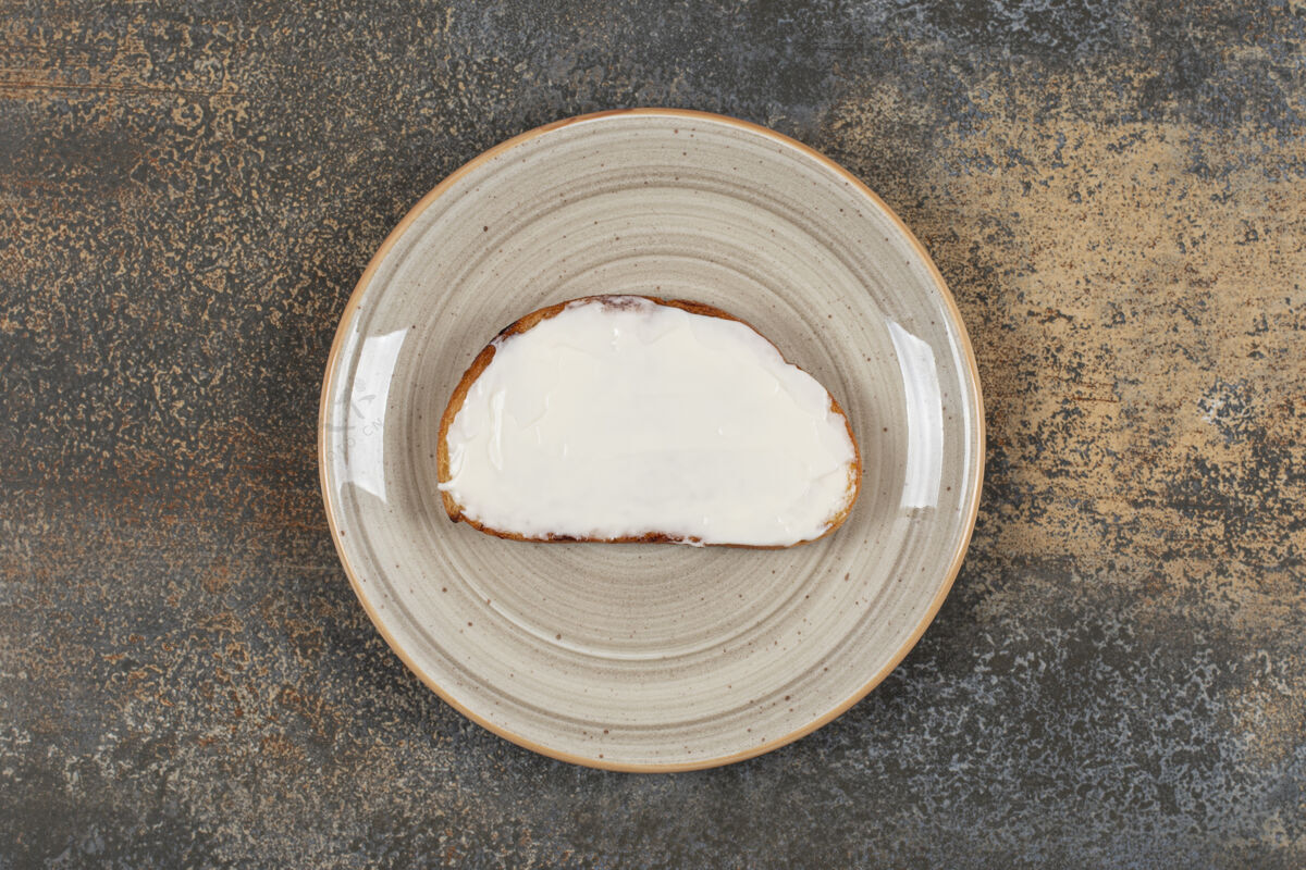 奶制品在陶瓷盘子上放一片烤面包和酸奶油酸奶油小吃涂抹