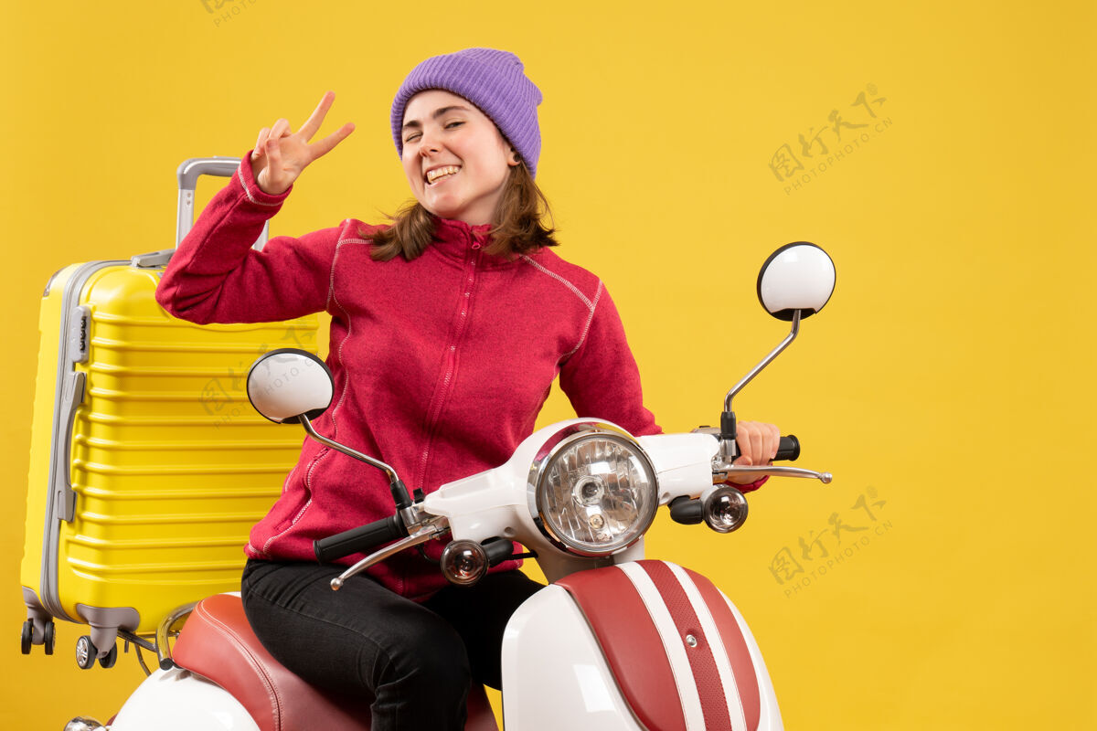 传送带前视图：年轻女孩眨着眼睛在轻便摩托车上做着胜利的手势胜利摩托车快乐