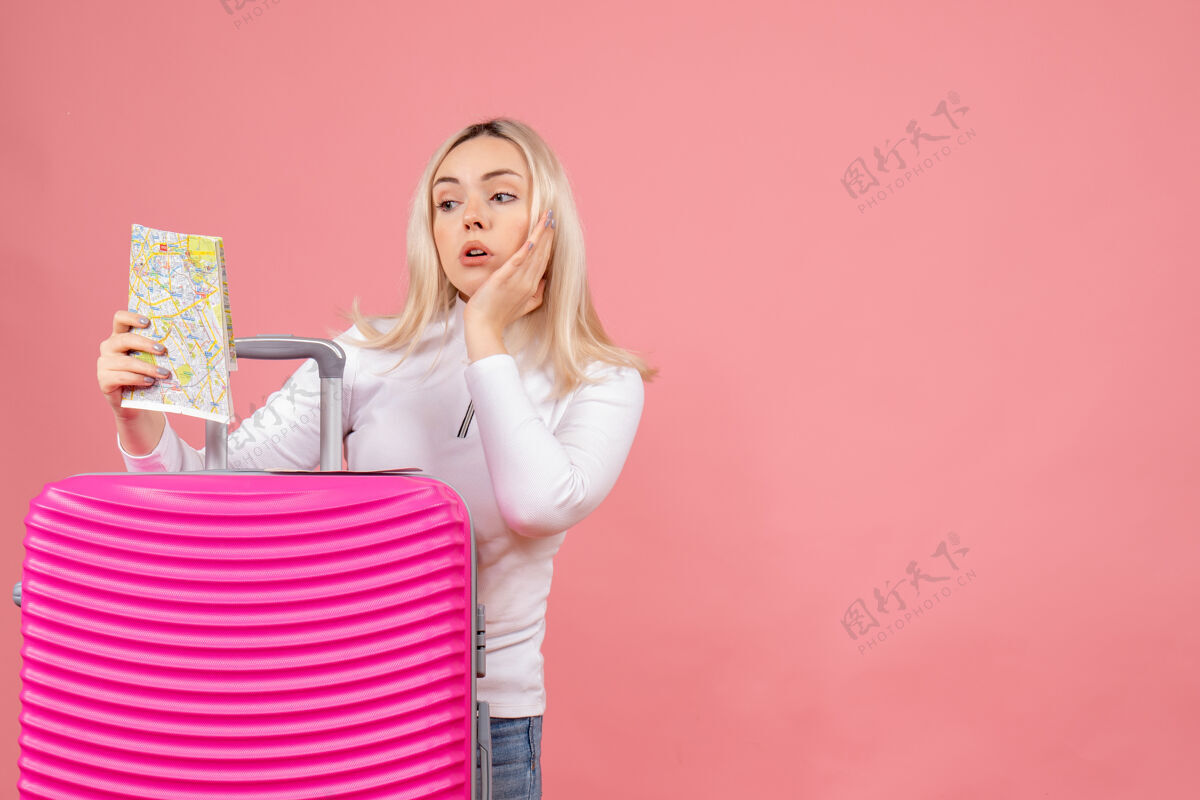 快乐前视图：年轻女士站在粉色手提箱后面看地图站在前面女士成人