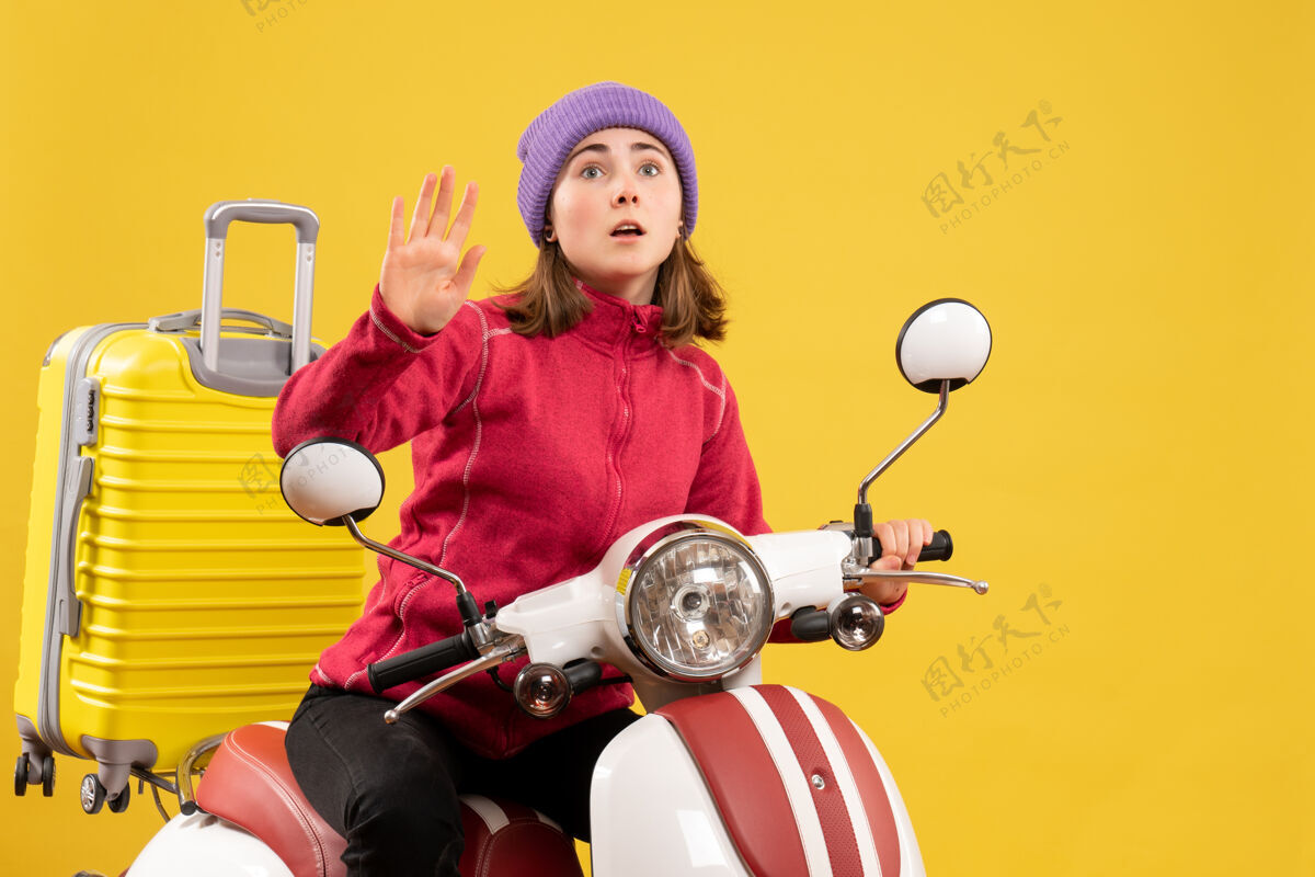 摩托车前视图：骑着轻便摩托车的年轻女孩在挥手球摩托车传送带
