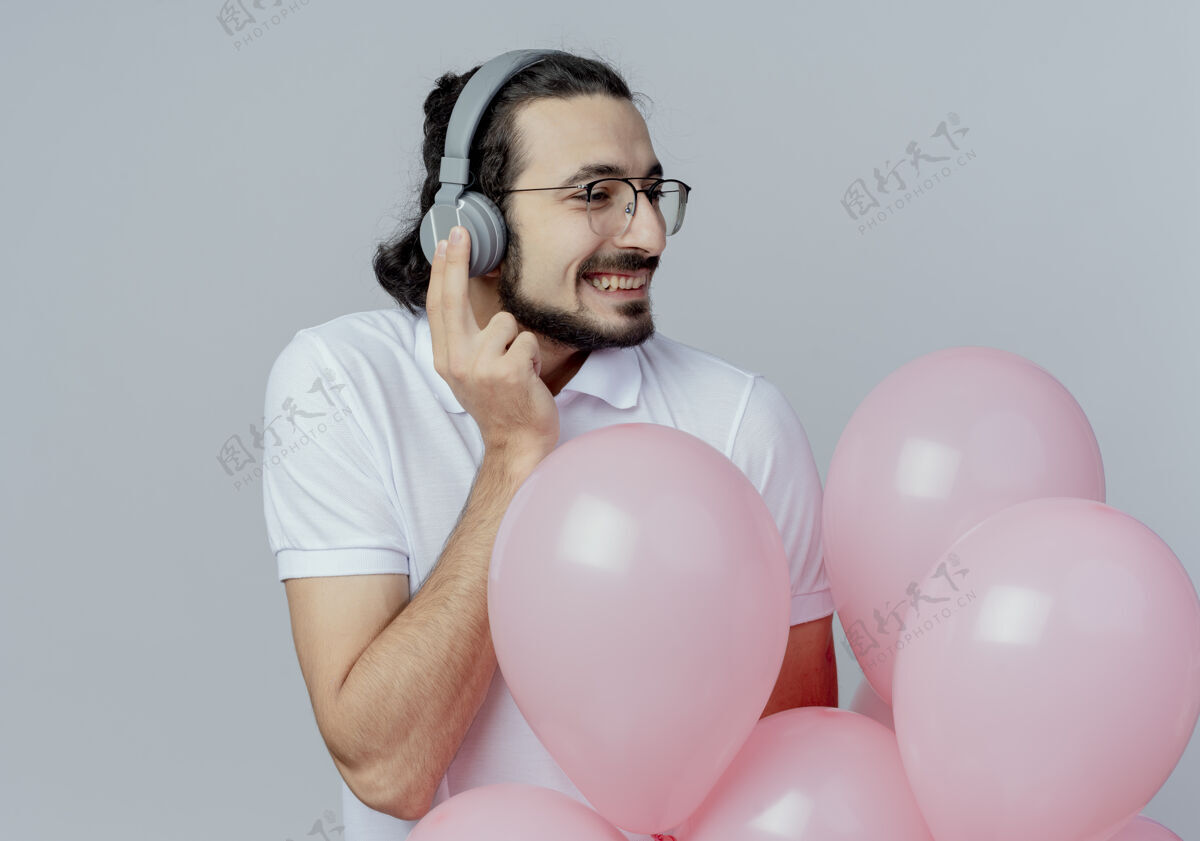 男人看着身边微笑的帅哥戴着眼镜和耳机拿着气球帅气耳机白色