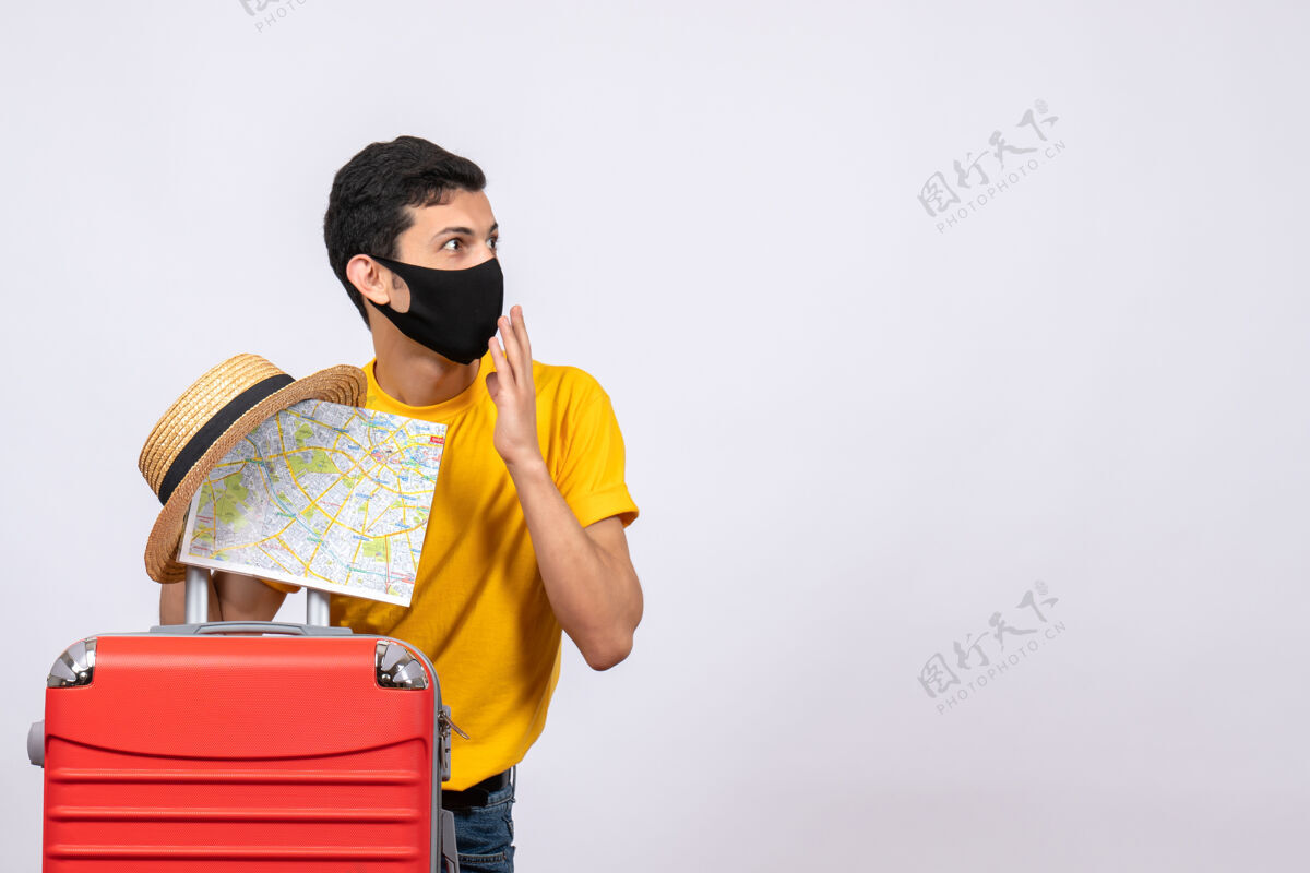 地图正面图：穿着黄色t恤和红色手提箱的年轻人 手里拿着草帽和地图年轻人帽子人