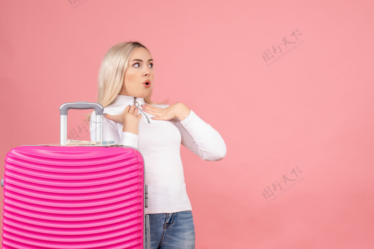成人前视图：一个穿着粉色手提箱的漂亮女人在看什么东西时尚正面女士
