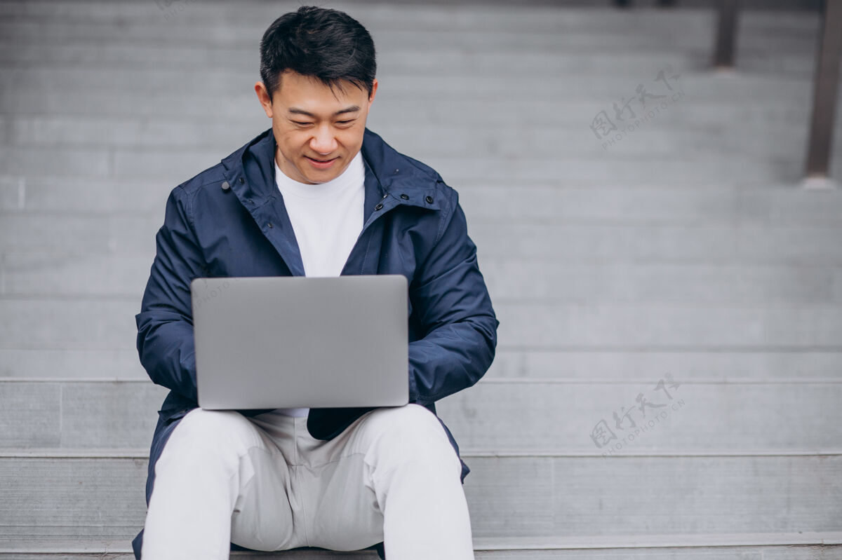 中文亚洲商人坐在楼梯上工作在电脑上男人候选人朋友
