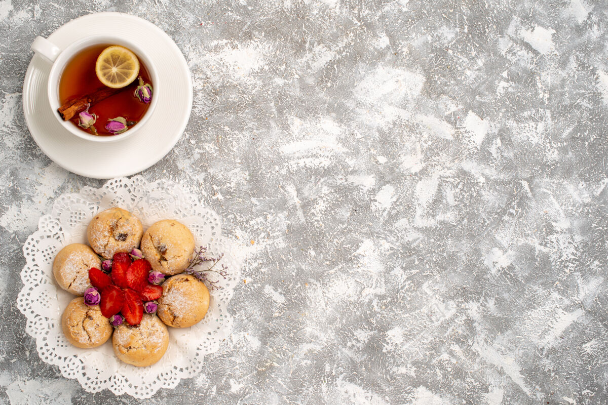 食物俯瞰美味的沙曲奇与草莓和一杯茶在白色的表面糖水果浆果