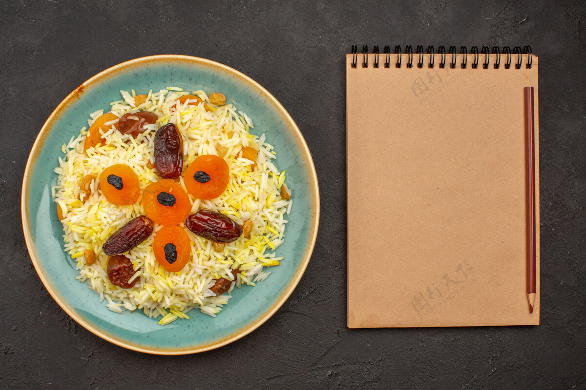 午餐美味的煮熟普洛夫米饭与不同的葡萄干在深灰色的表面盘内俯视食物早餐不同的