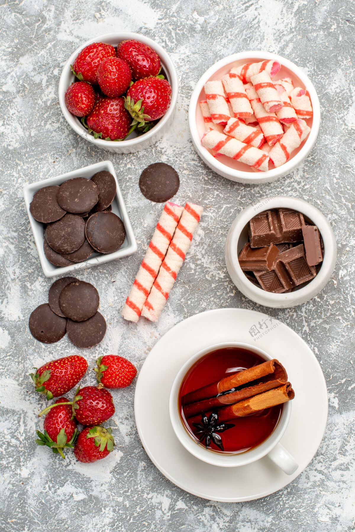 膳食顶视图碗与草莓巧克力糖果和肉桂八角种子茶马赛克灰白色地面浆果糖果种子