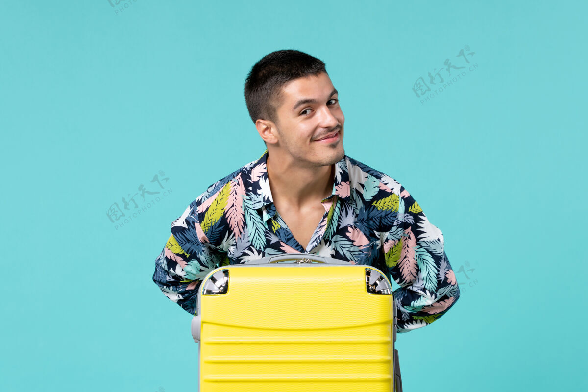 人年轻男子正准备旅行 蓝色墙上放着他的黄包消费品旅行男人