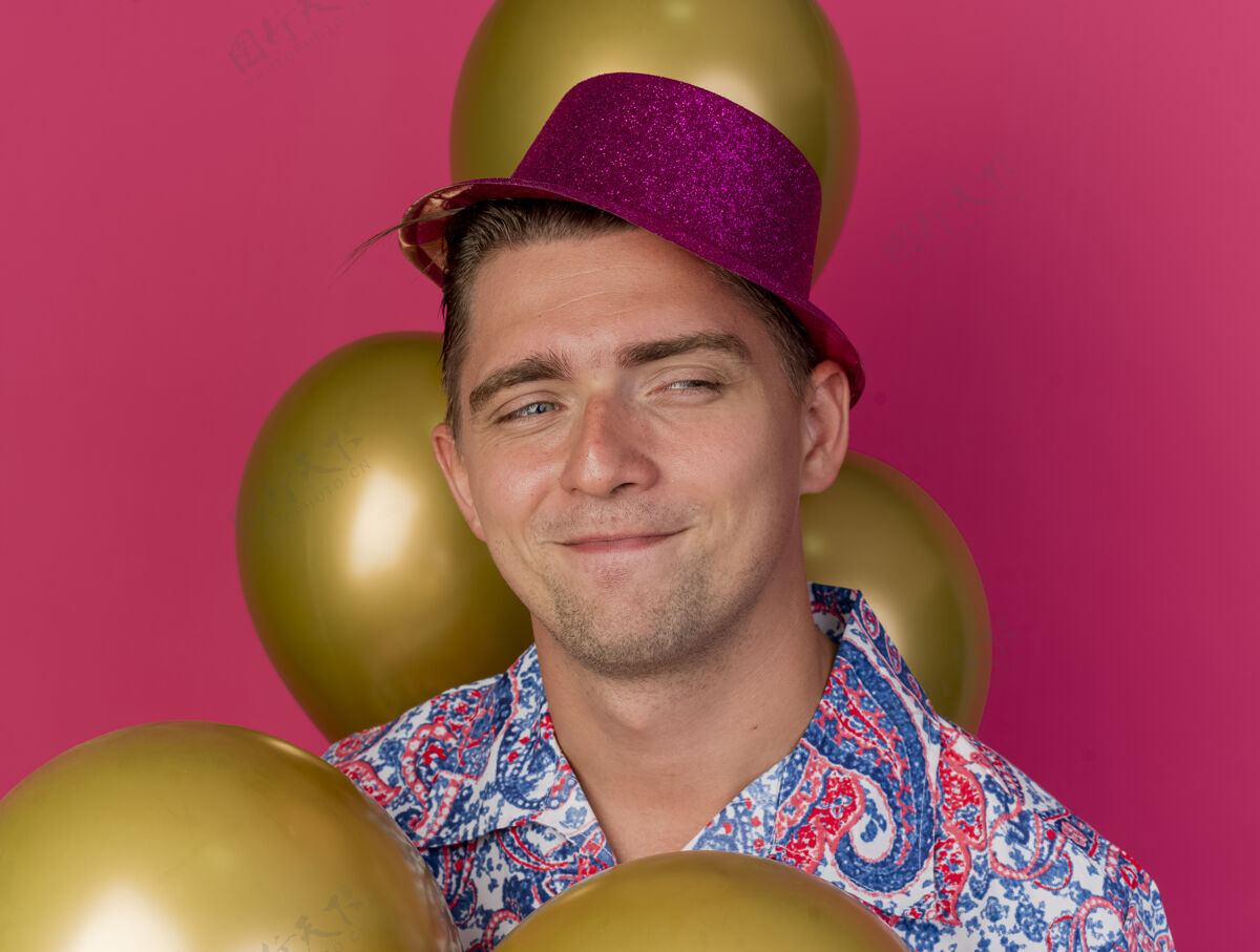 穿高兴的年轻人戴着粉红色的帽子站在气球孤立的粉红色站粉色请