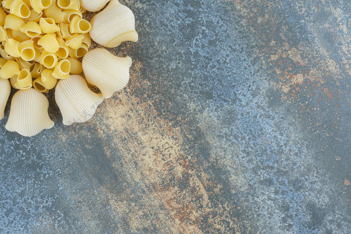 碗煮熟的和未煮熟的意大利面放在碗里 放在大理石背景上生食烟斗意大利面食