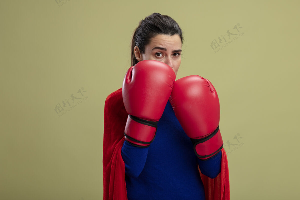 手套自信的年轻超级英雄女孩戴着拳击手套站在橄榄绿的孤立无援的战斗姿势站立穿着自信