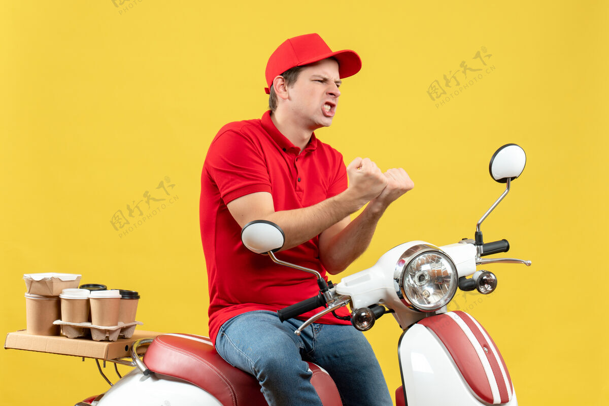 人顶视图雄心勃勃的情绪化的年轻人穿着红色衬衫和帽子在黄色背景下传递命令交付成人坐着