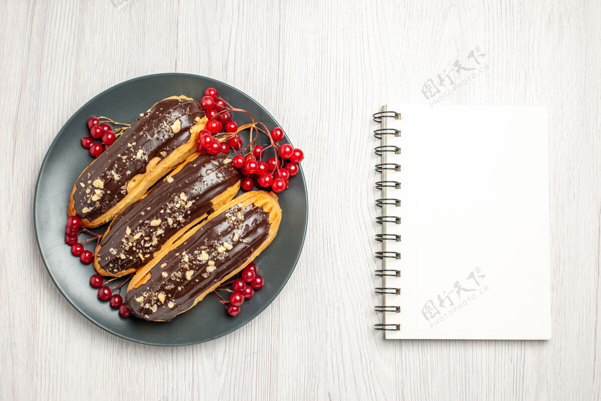 礼品俯瞰图：灰色盘子上的巧克力和葡萄干 白色木桌上的笔记本设备餐馆头发幻灯片