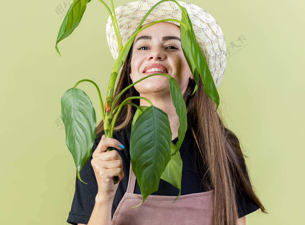 帽子微笑美丽的园丁女孩穿着制服戴着园艺帽脸上的植物隔离橄榄绿脸橄榄色绿色