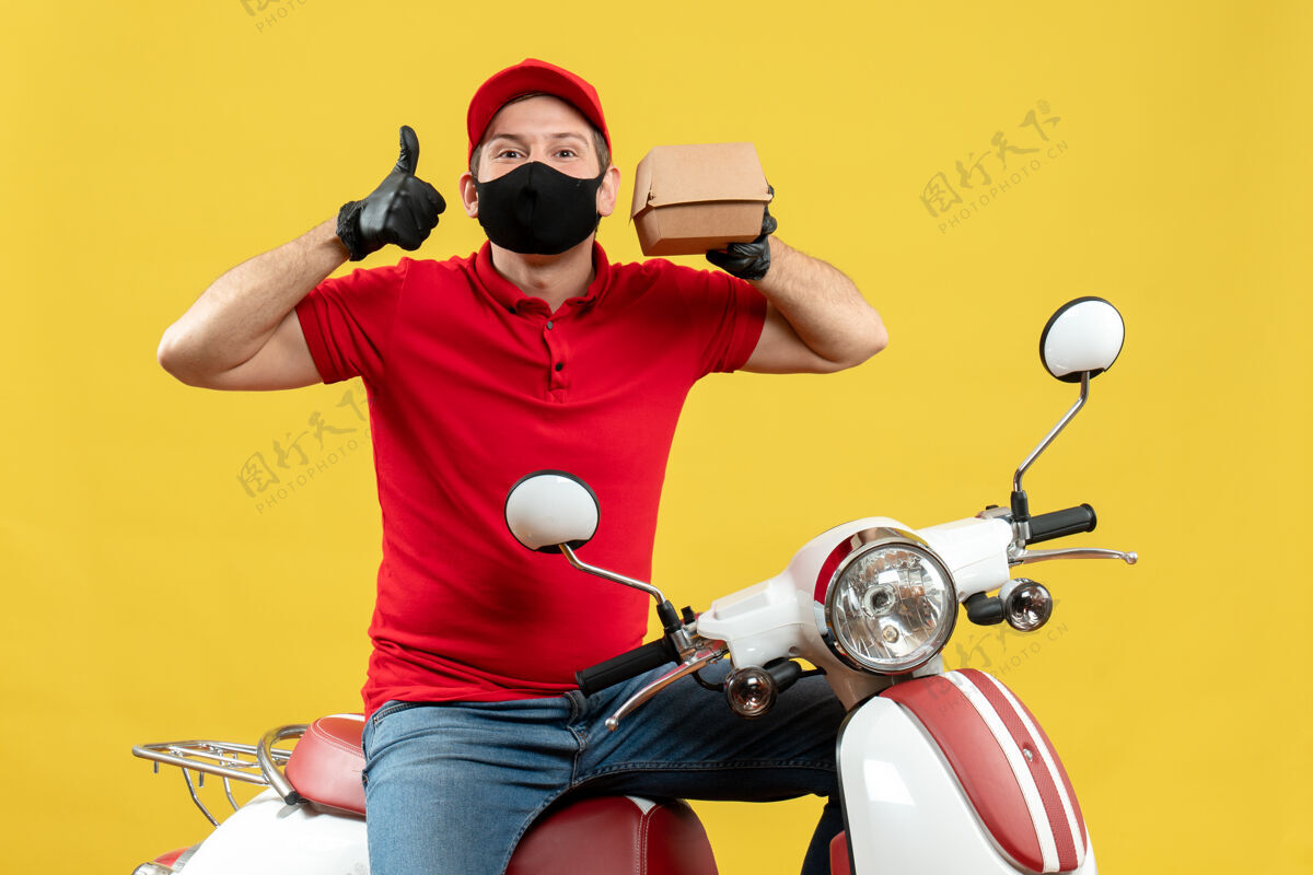 车辆顶视图送货员穿着红色上衣 戴着帽子手套 戴着医用面罩 坐在滑板车上 拇指朝上 显示秩序摩托车运动医疗