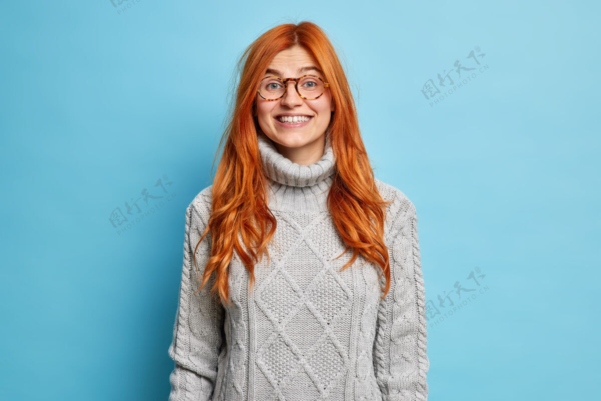 成人可爱的红发女青年 欧式外表 微笑着 穿着暖和的毛衣 表达积极的情绪 听到好消息眼镜红色人