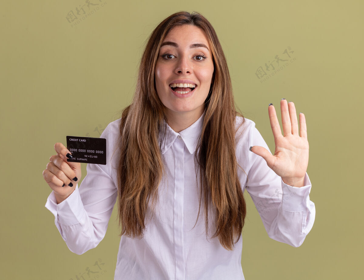 信用高兴的年轻漂亮的白人女孩持有信用卡 并在橄榄绿的手势五请绿色手势