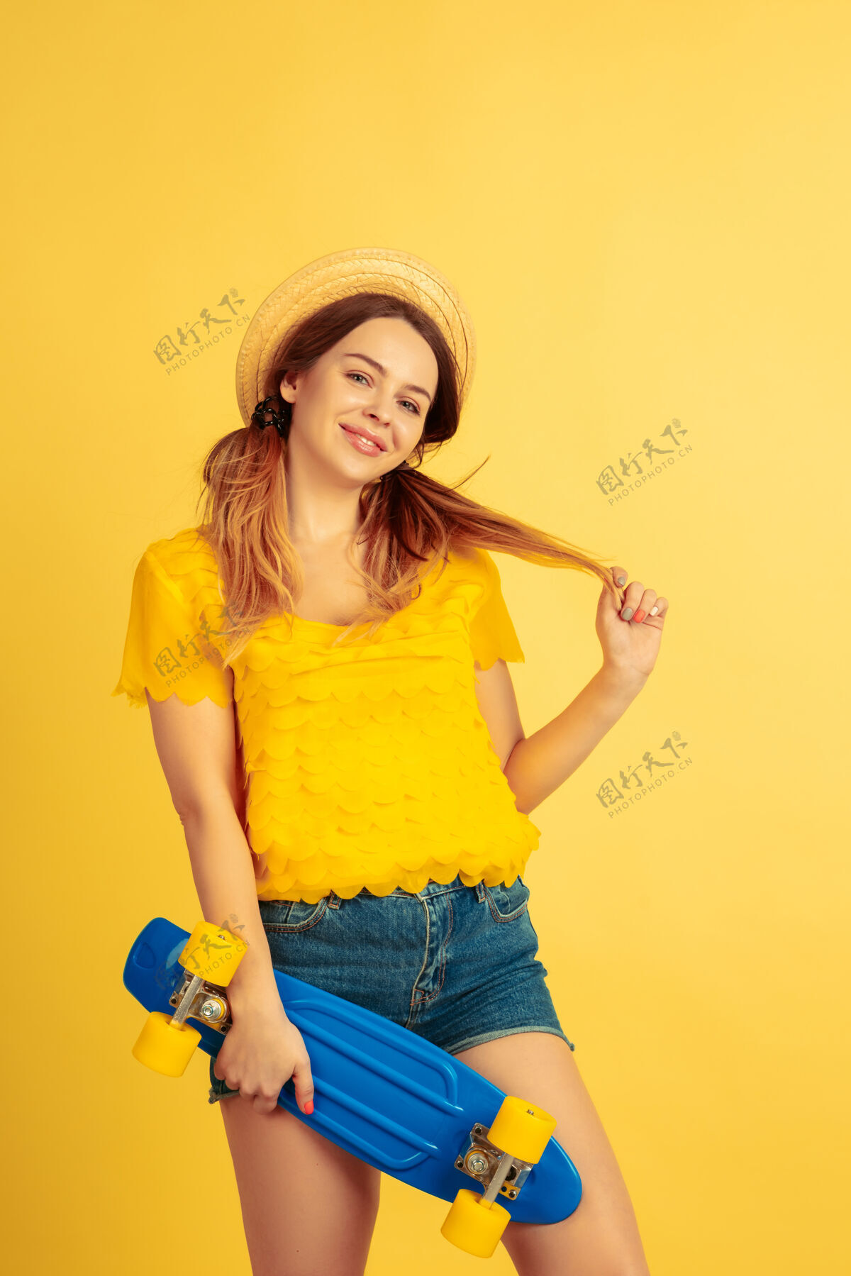 公司梦幻般的 拿着溜冰鞋黄色工作室背景上的白种女人肖像戴着帽子的漂亮女模特人类情感的概念 面部表情 销售 广告夏日 旅游 度假主管情感事业