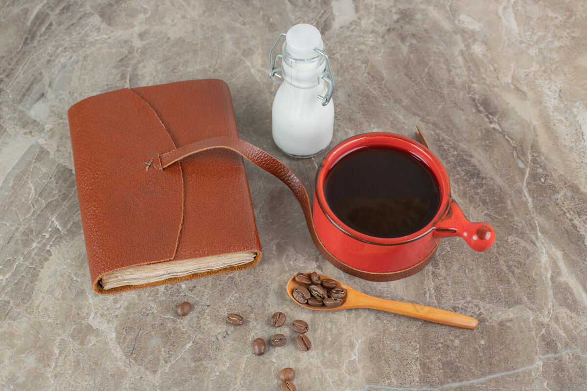 豆咖啡杯 咖啡豆和笔记本放在大理石表面勺子香味浓缩咖啡