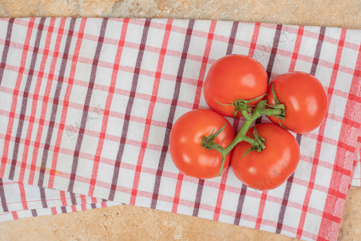 有机桌布上放着一堆新鲜的红西红柿和绿茎生的新鲜饮食