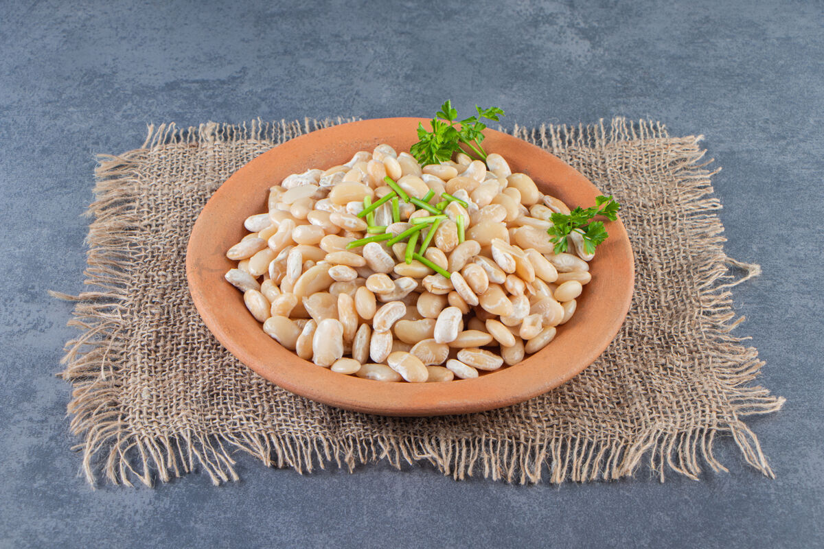 饮食白豆放在盘子上的粗麻布餐巾上的大理石表面莳萝有机谷物
